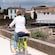 A woman pedaling a bicycle in a European countryside